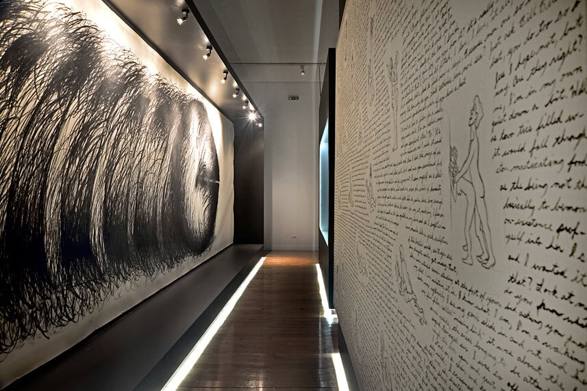 Contemporary art installation with large black and white drawings and handwritten text.