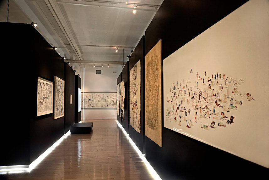 Modern art gallery with black walls and illuminated artwork displays.