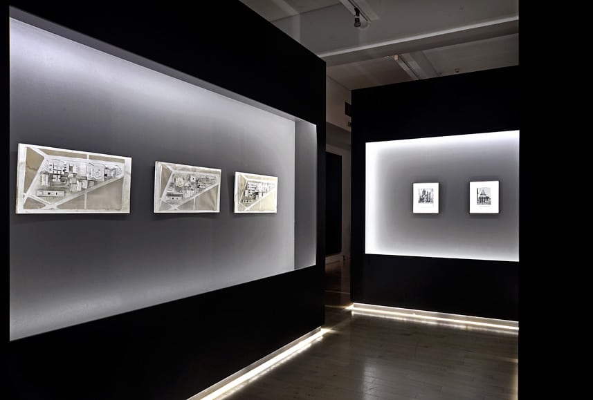 Modern art gallery display with black walls and illuminated artwork.