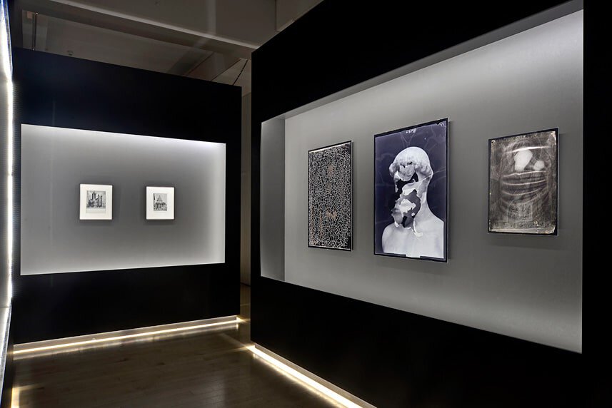 Modern art gallery display with framed artworks on sleek black and gray walls.