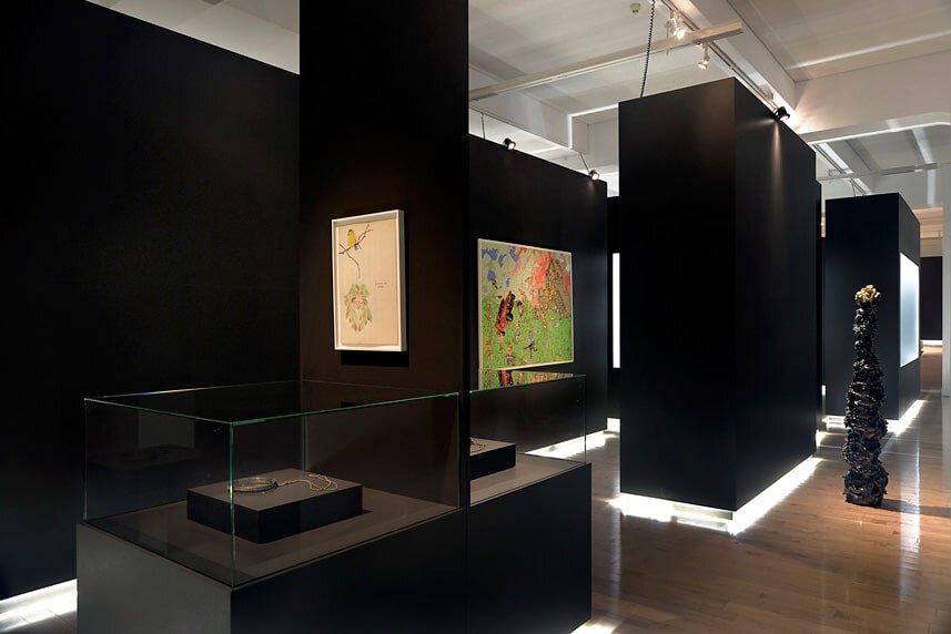 Modern art gallery interior with black display walls and artwork exhibits.