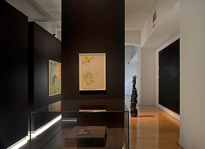 Modern art gallery interior with black walls and colorful artwork displays.