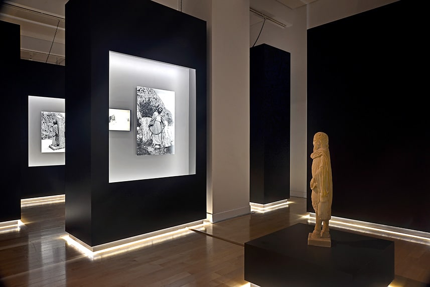 Modern art gallery with illuminated black display walls and sculptures.