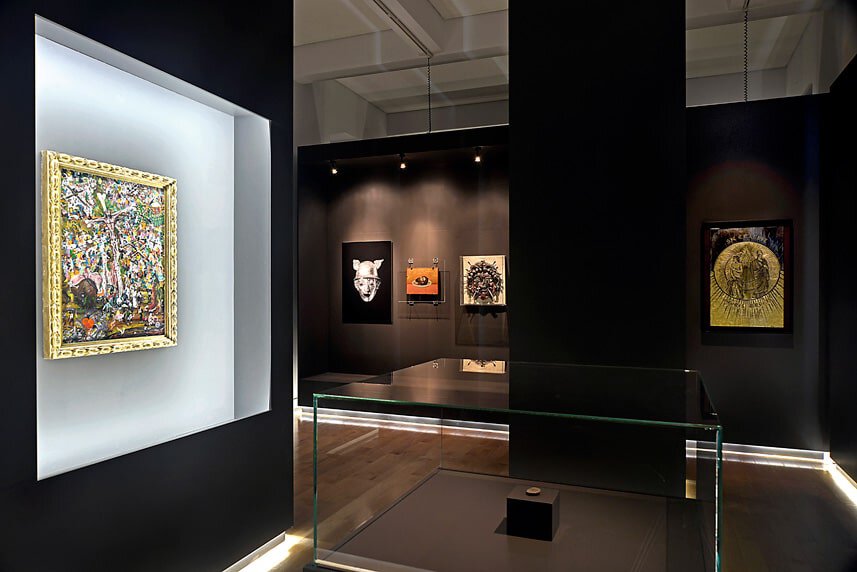 Modern art gallery display with colorful paintings and sculptures in a sleek black setting.