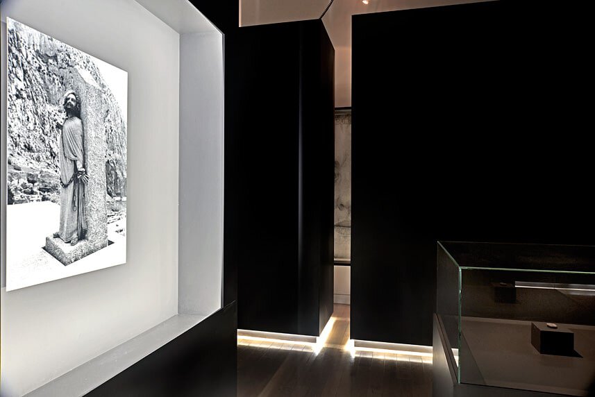 Modern art gallery interior with black walls and a black-and-white photograph.