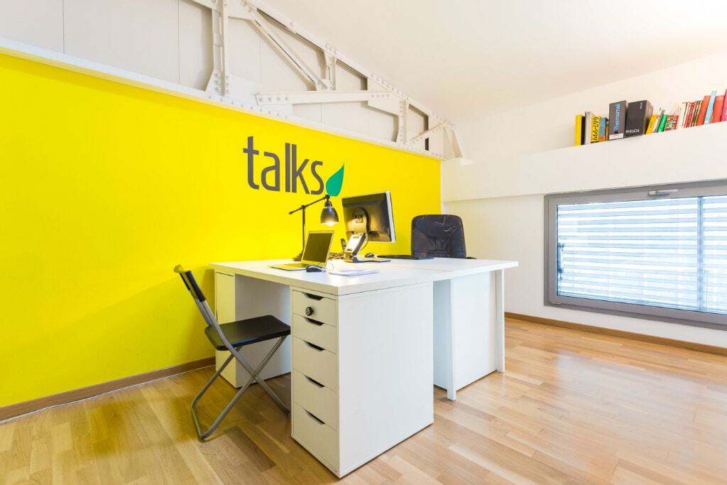 Modern office space with yellow accent wall and white desk setup.