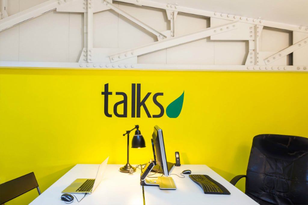 Modern office space with bright yellow wall and minimalist desk setup.