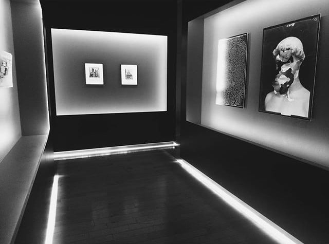 Modern art gallery with illuminated artwork and sculptures in black and white.