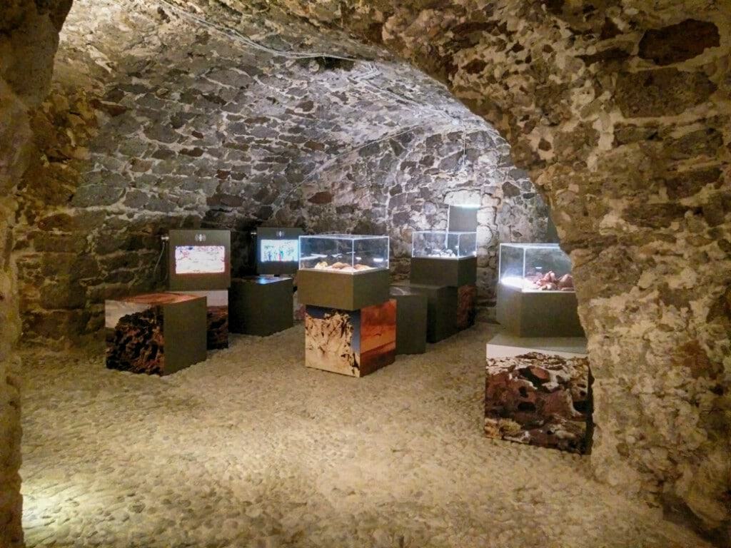 Exhibition inside a historic stone cave with display cases.
