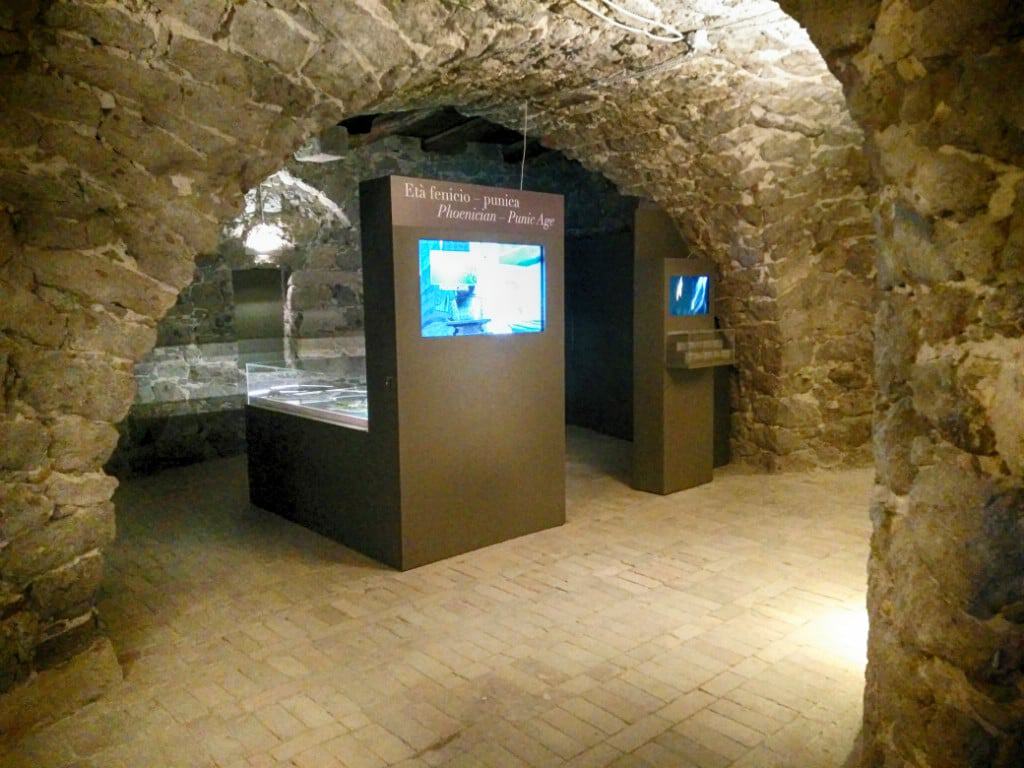 Exhibition display inside historic stone vault at Torre San Vittorio museum.