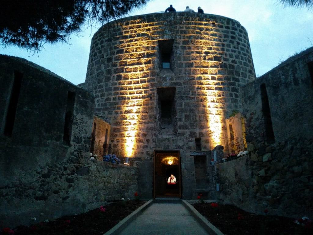 Night view of Torre San Vittorio, a historic stone fortress in Carloforte.