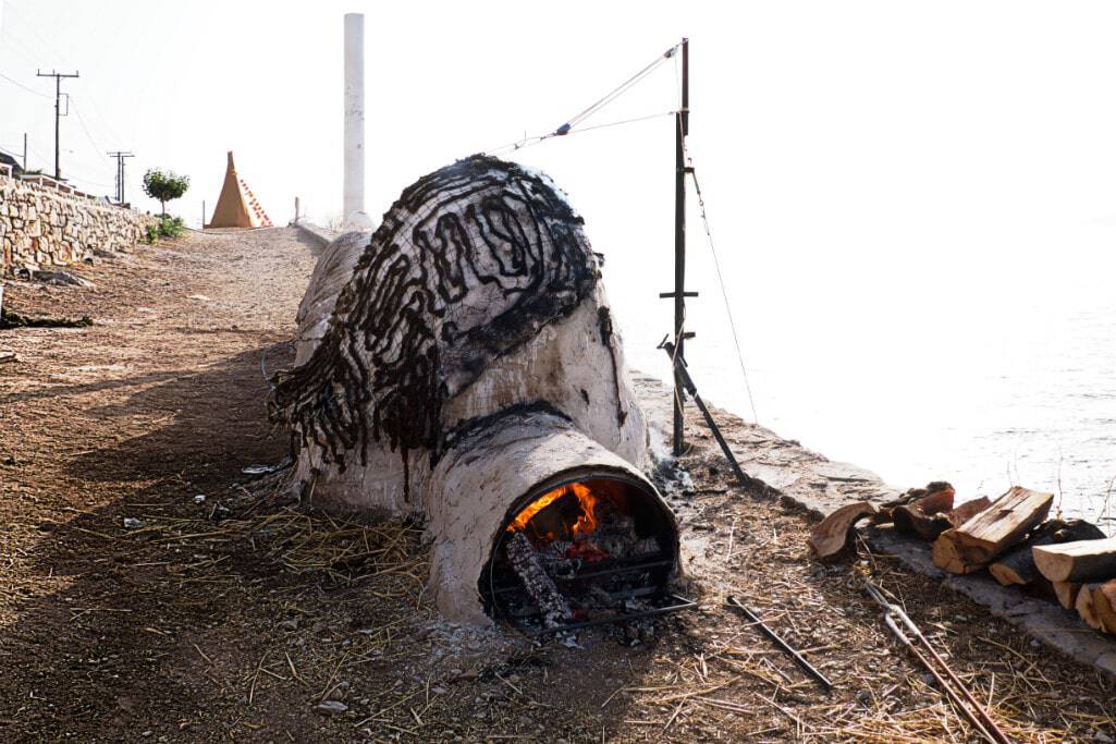 Unique outdoor oven with a chimney and fire inside, rustic setting.