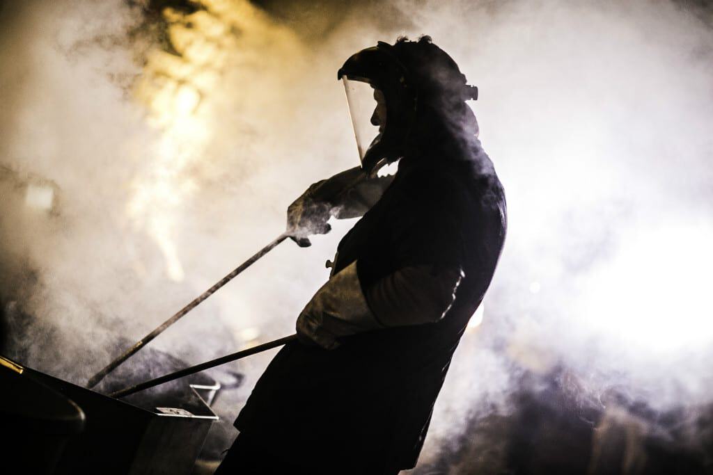 Chef cooking with smoke and steam in a professional kitchen setting.