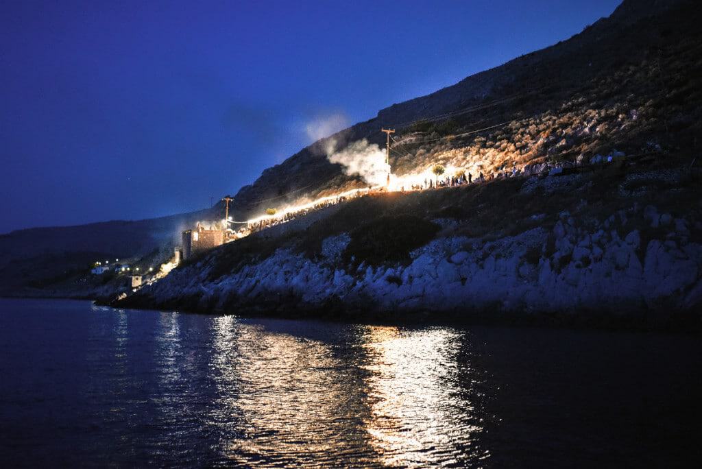 Night view of Putiferio with illuminated buildings and smoke on a hillside.