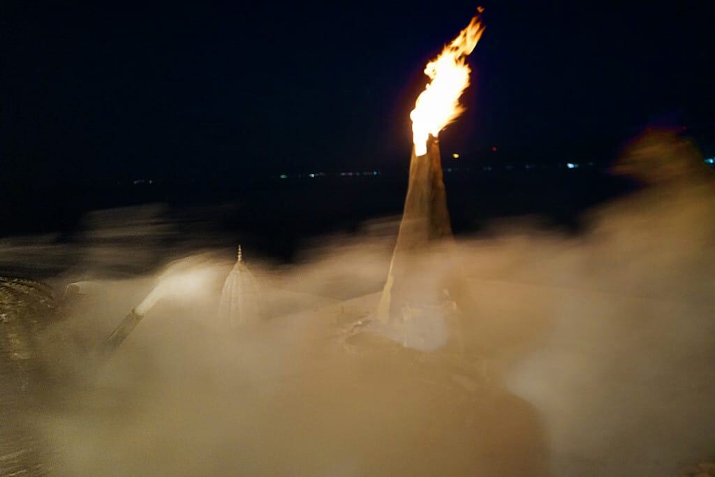 Industrial chimney emitting fire and smoke at night.
