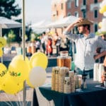 People At A Media Party With Balloons And Coffee Stands Outdoors.