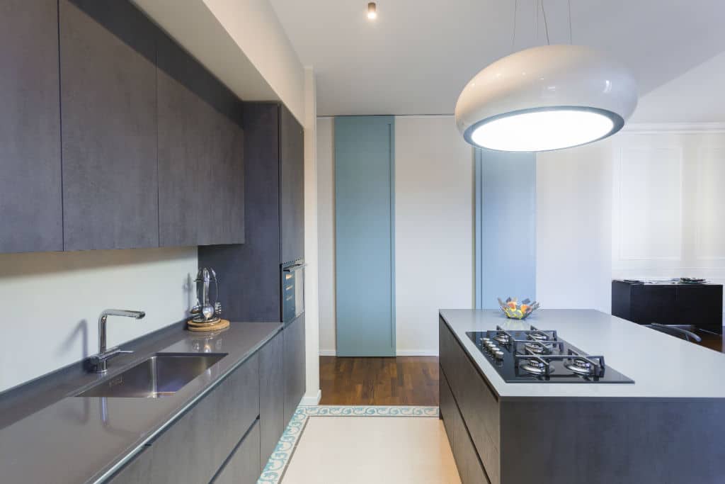 Modern kitchen with sleek dark cabinetry and a central island with a cooktop.