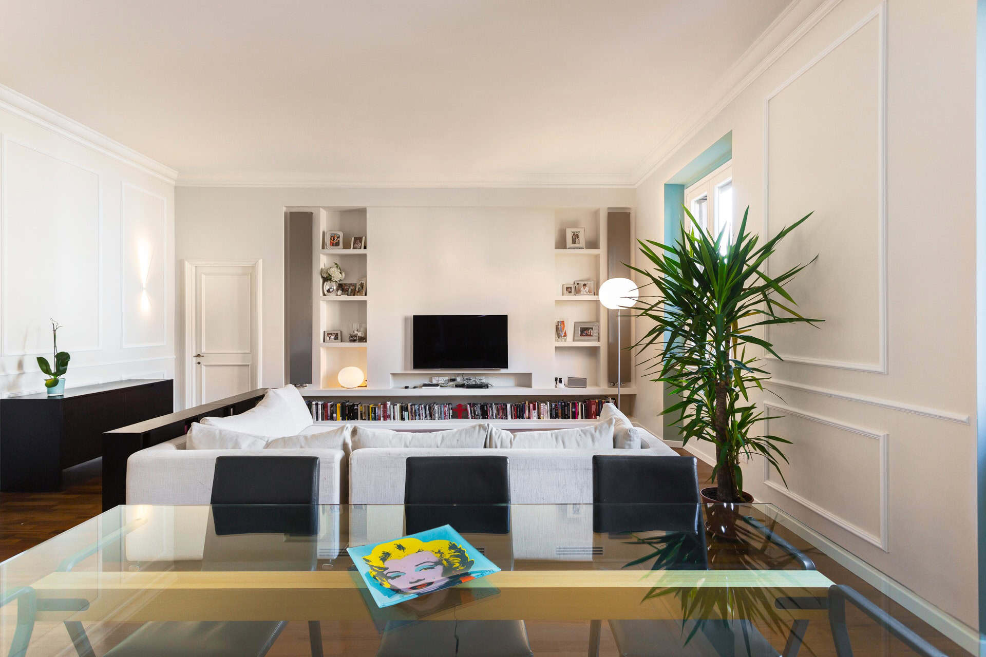 Modern living room with white walls, large TV, and stylish decor.