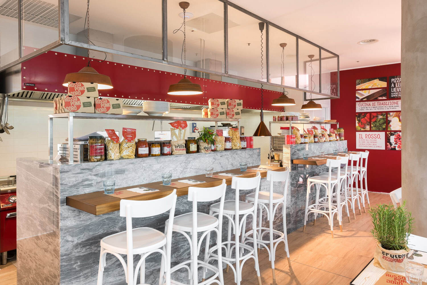 Modern restaurant interior with a marble bar and white chairs, featuring Italian food products.