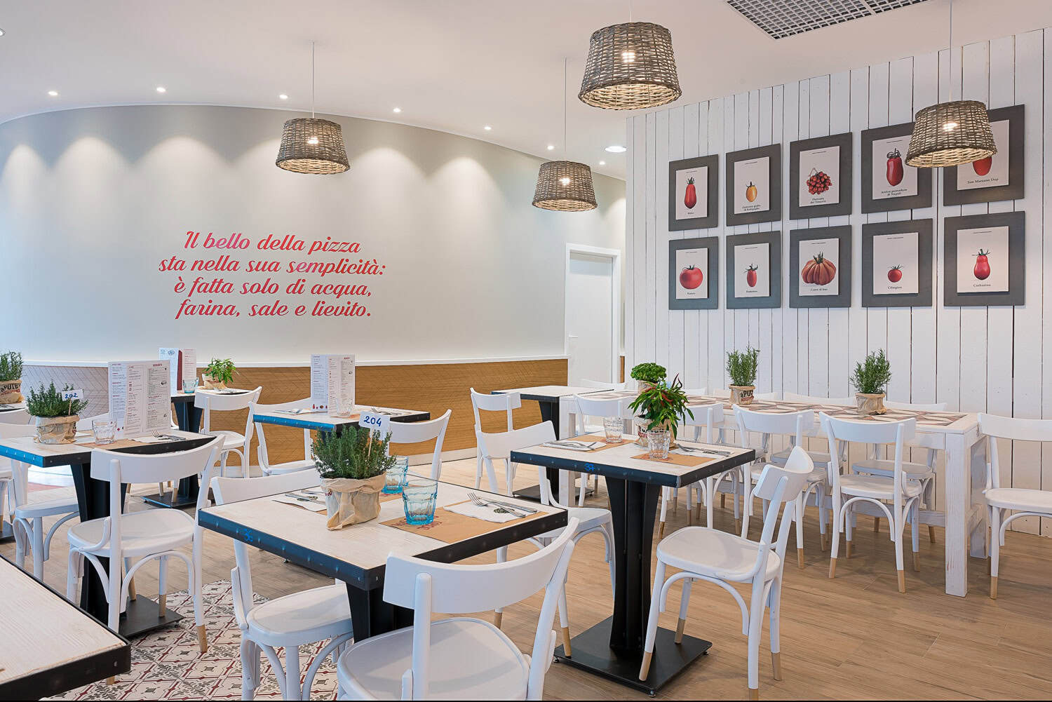 Modern restaurant interior with white and black furniture and framed artwork on the wall.