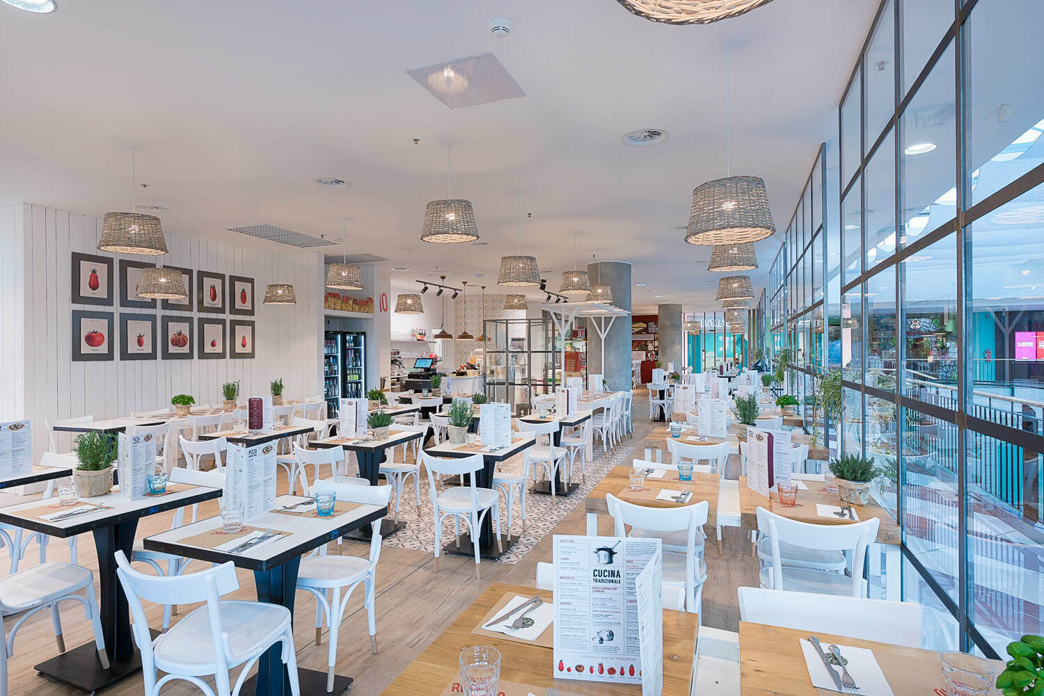 Modern restaurant interior with white furniture and large glass windows.