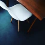 Contemporary White Chair With Wooden Legs Next To A Wooden Table In Modern Interior.