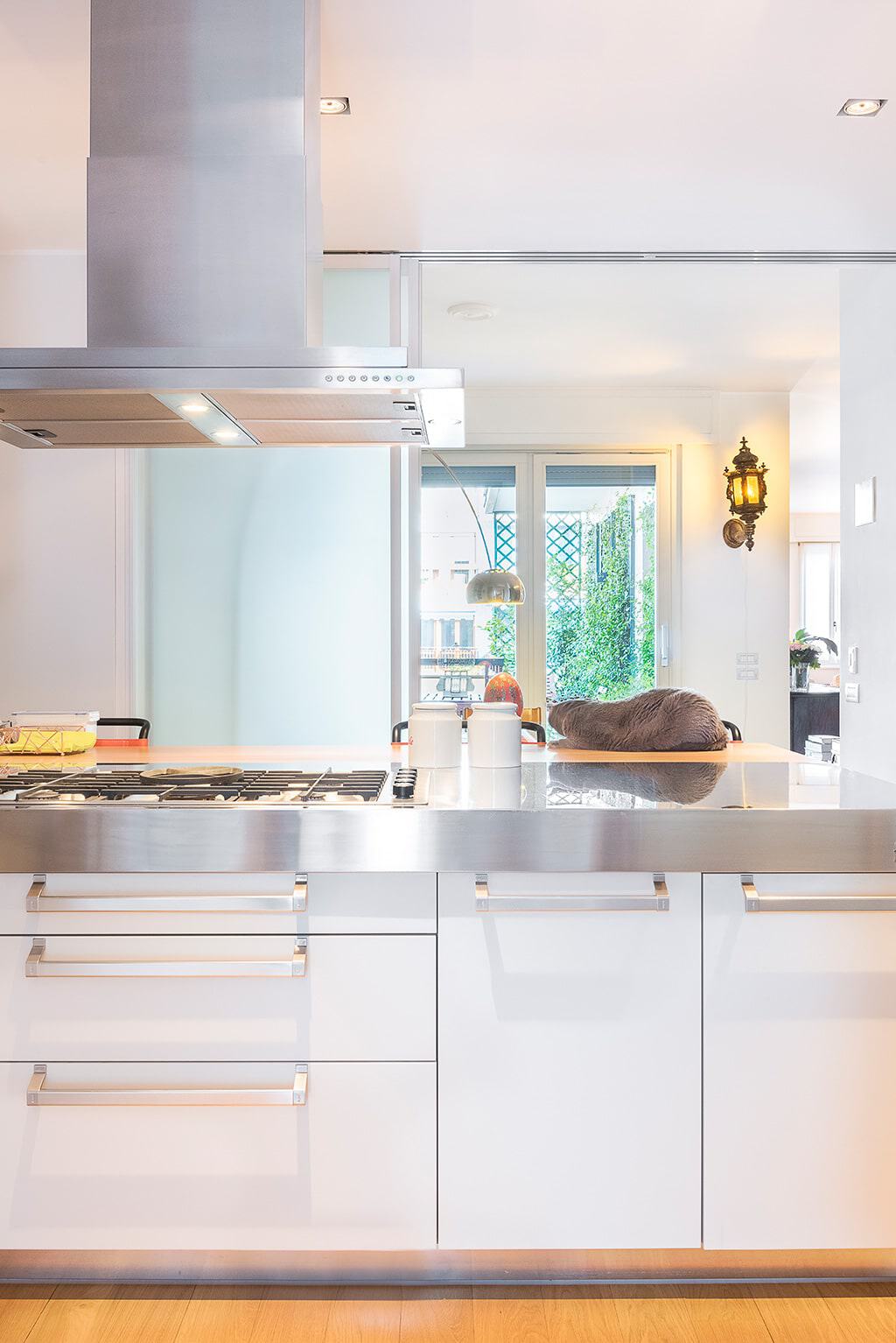 Modern white kitchen with stainless steel appliances and natural light.