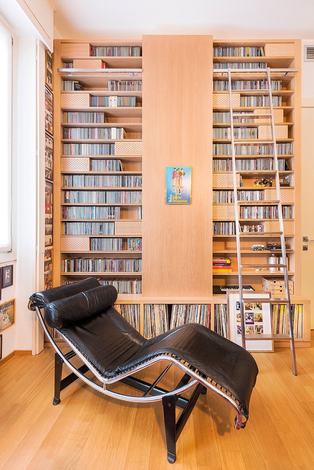 Modern wooden bookshelf filled with CDs and books in a cozy library setting.