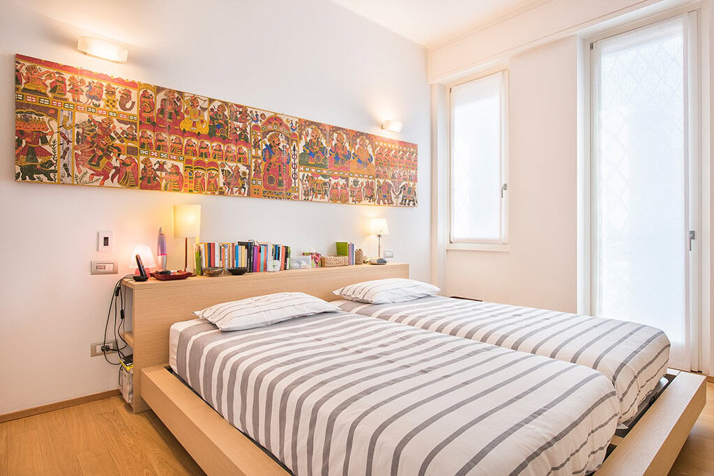 Modern bedroom with striped beds and colorful artwork above the headboard.