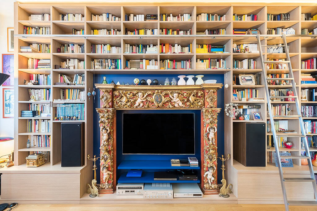 Modern library with ornate fireplace and extensive bookshelves.