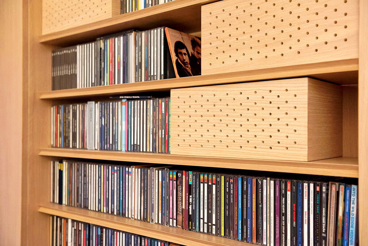 Bookshelf filled with CDs and wooden storage boxes in a modern library setting.