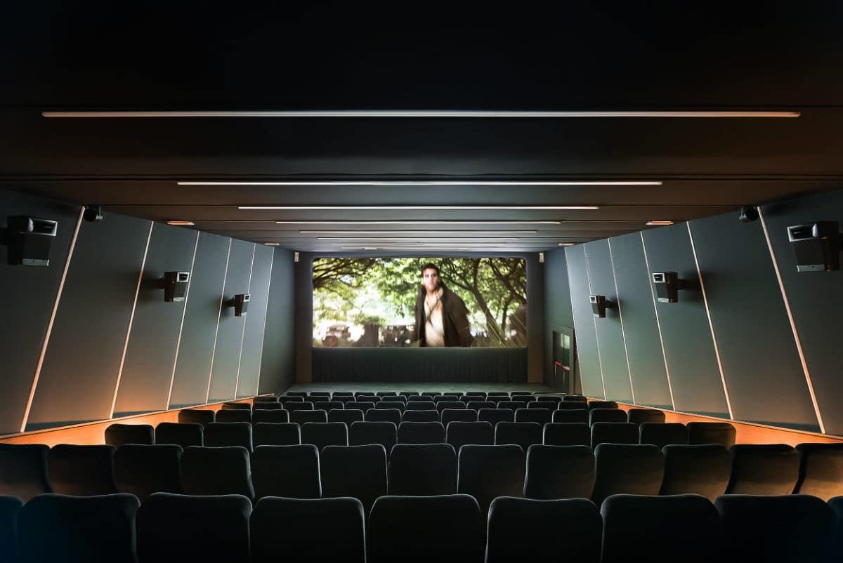 Modern multiplex cinema interior with large screen and comfortable seating.