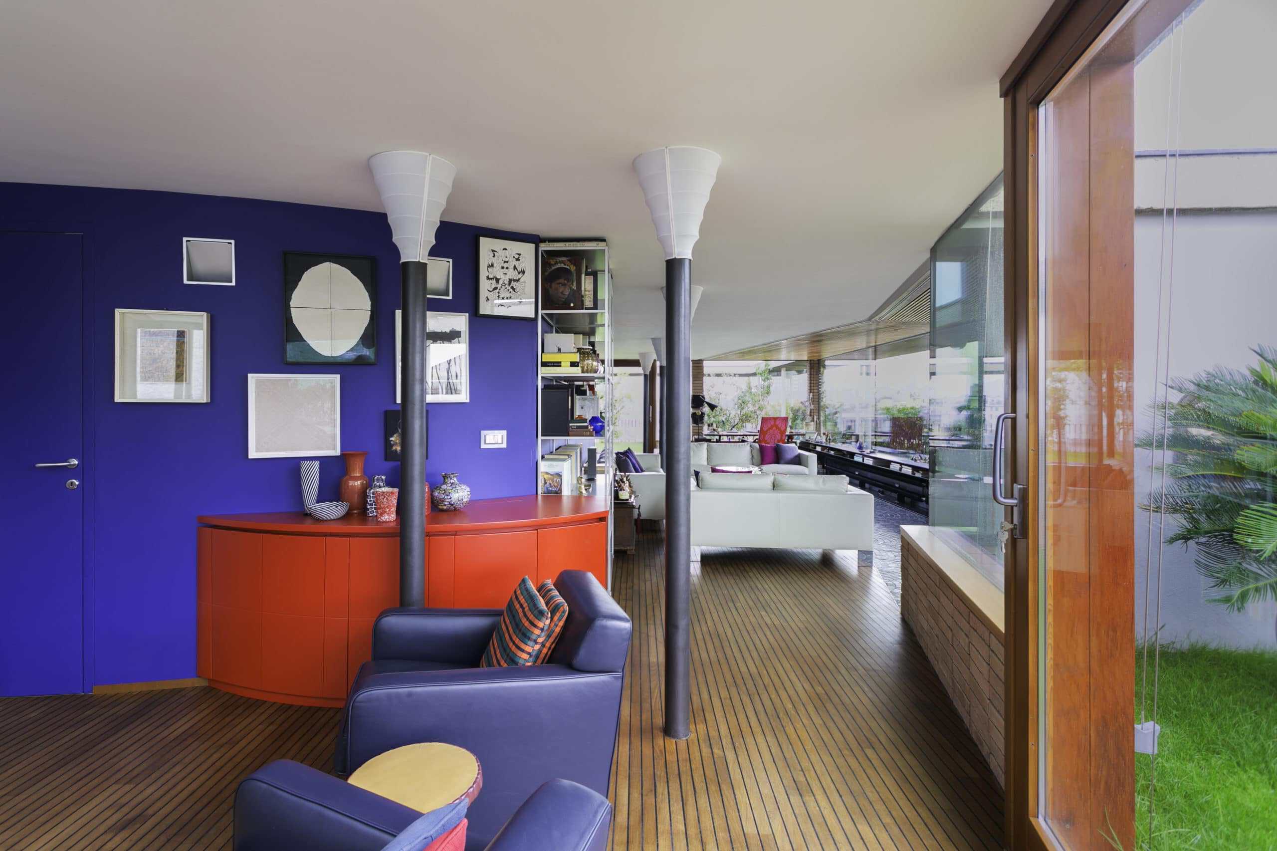 Modern living room with vibrant blue wall and stylish furniture.