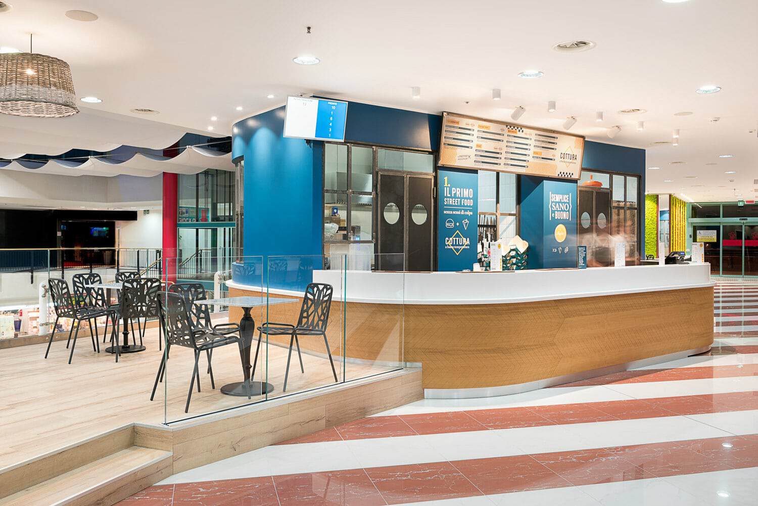 Modern food court kiosk with seating area in shopping mall.