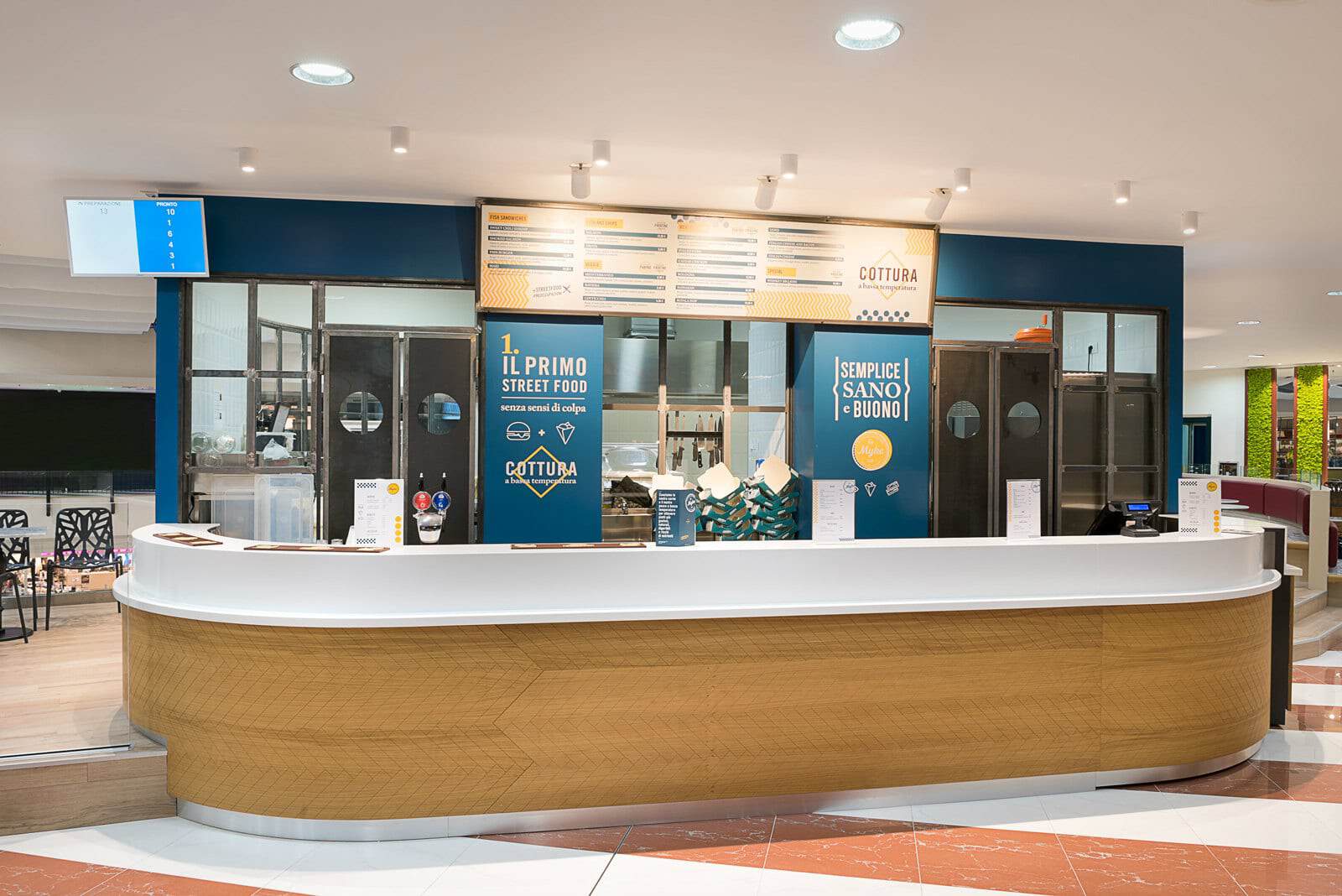 Modern food counter at Myke Fish & Burger Gavirate with digital menu boards.