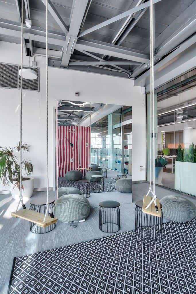 Modern office lounge with swings, poufs, and contemporary decor.