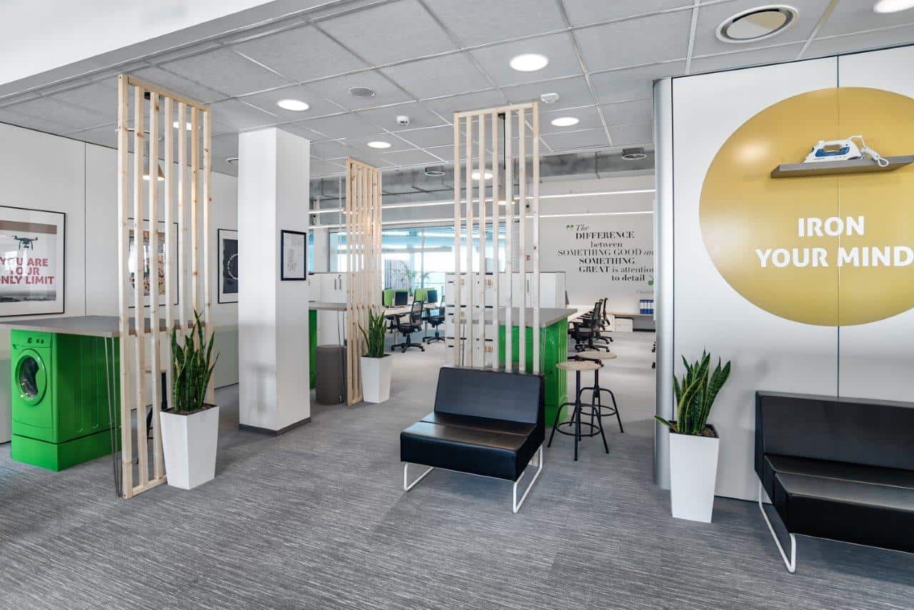 Modern office interior with green accents and wooden room dividers.