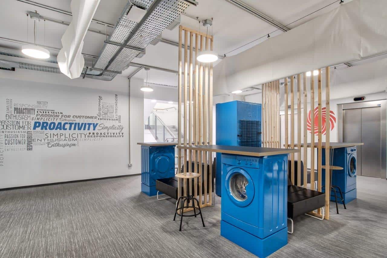 Modern office laundry area with blue washing machines and wooden dividers.