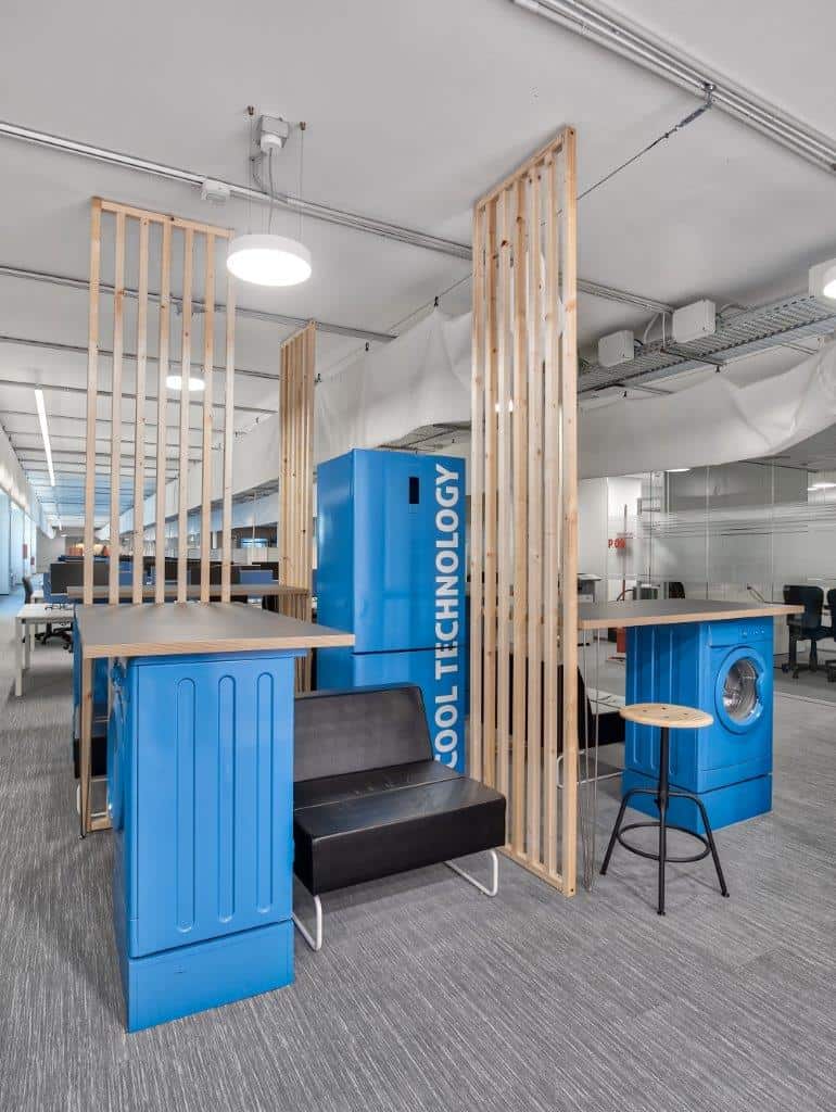 Innovative office space with blue tech-themed furniture and wooden dividers.