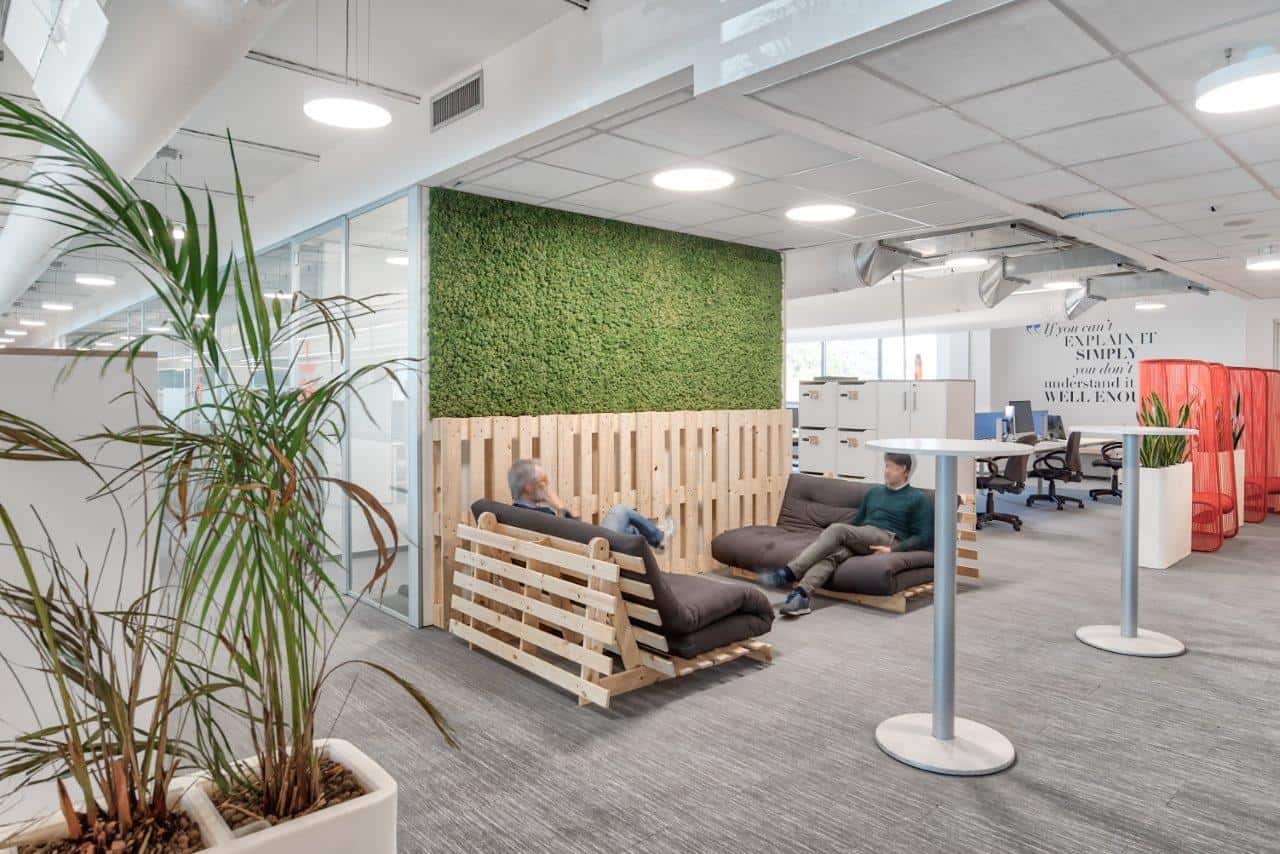 Modern office lounge area with green wall and comfortable seating.