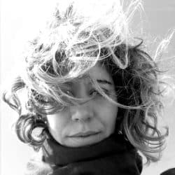 Black And White Portrait Of A Woman With Curly Hair And Wind-Blown Hairstyle.