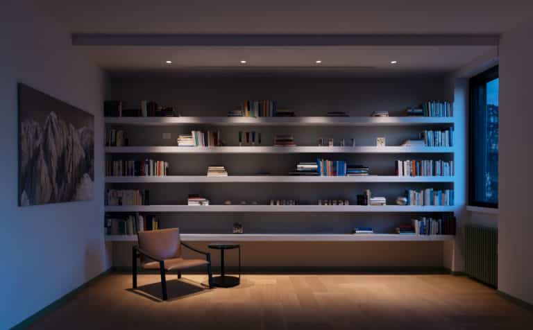 Modern Interior With Illuminated Bookshelves And Cozy Reading Corner Under Soft Lighting.