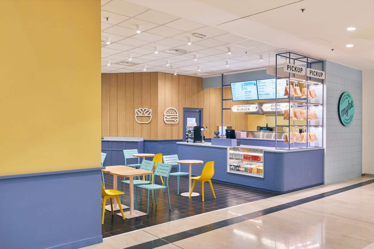 Modern fast-food counter with colorful seating area in a shopping mall.