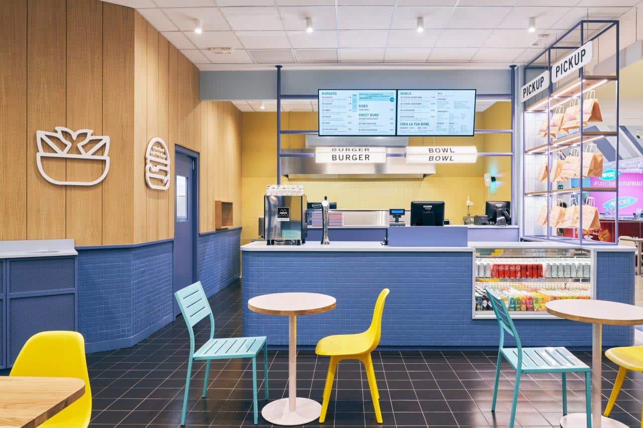Modern fast-food counter with colorful seating and digital menu boards.