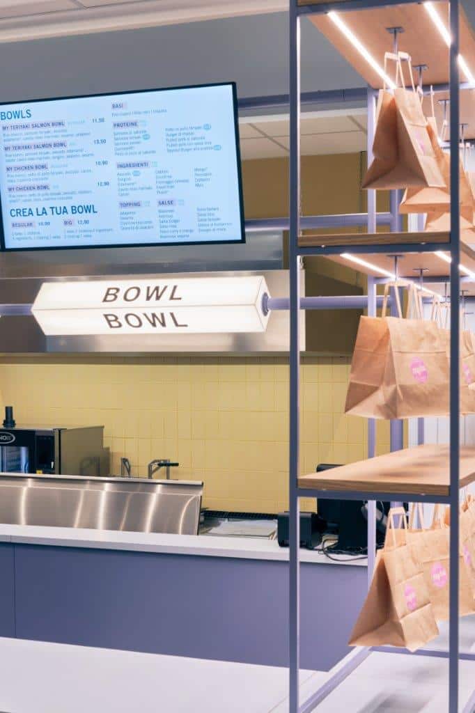 Modern fast-casual restaurant interior with digital menu and paper bags for takeout.