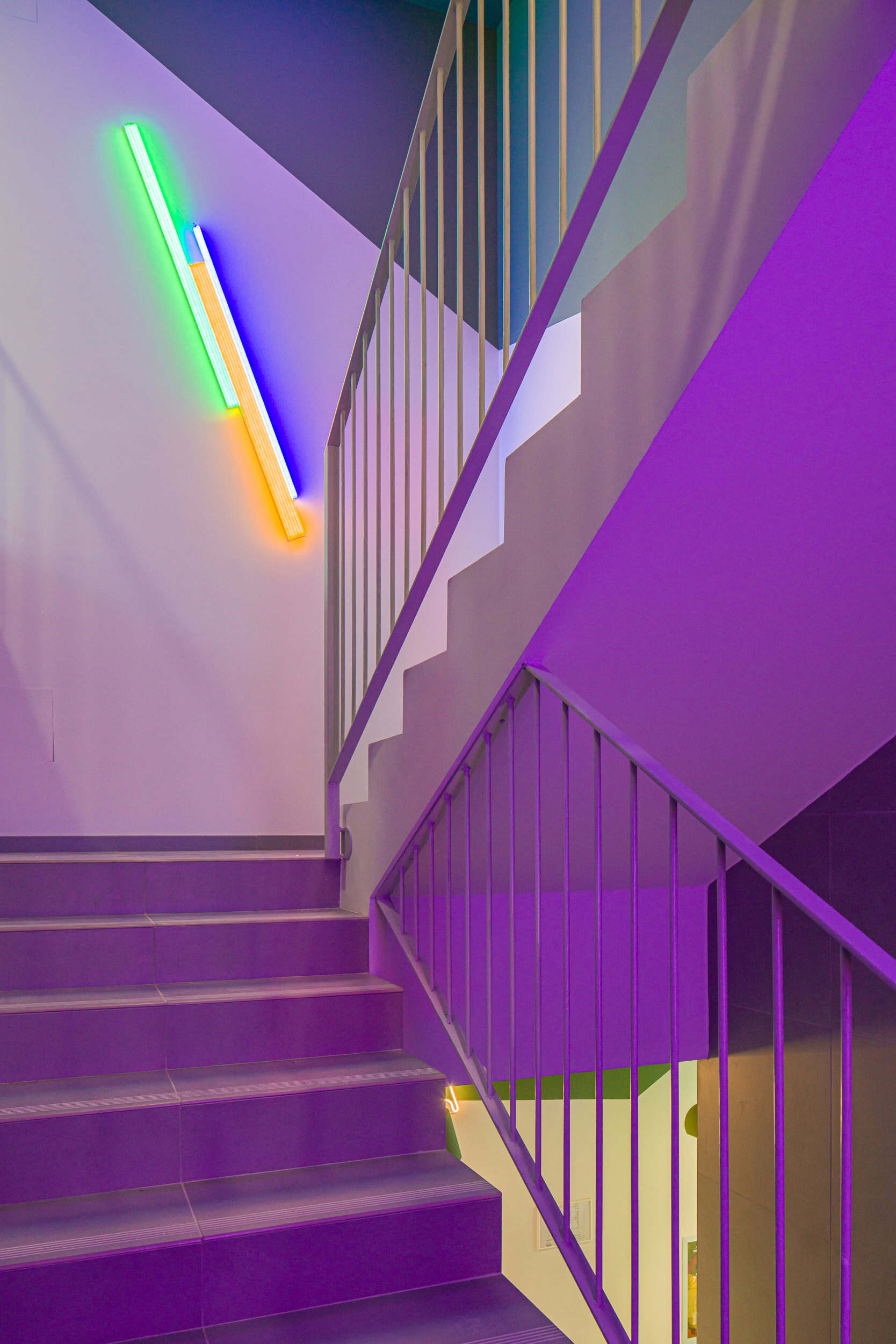 Colorful neon light installation on staircase wall in modern interior.