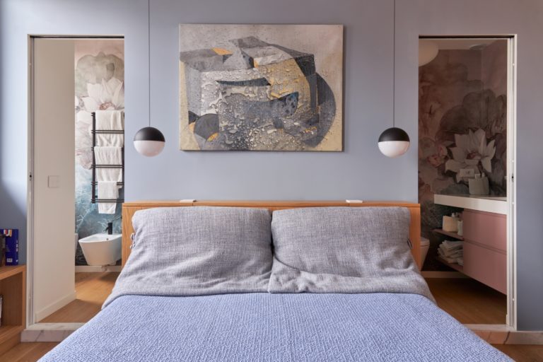 Periwinkle Master Bedroom With Oak Headboard And Twin Doors Leading To The Mirrored His-And-Hers Bathrooms.