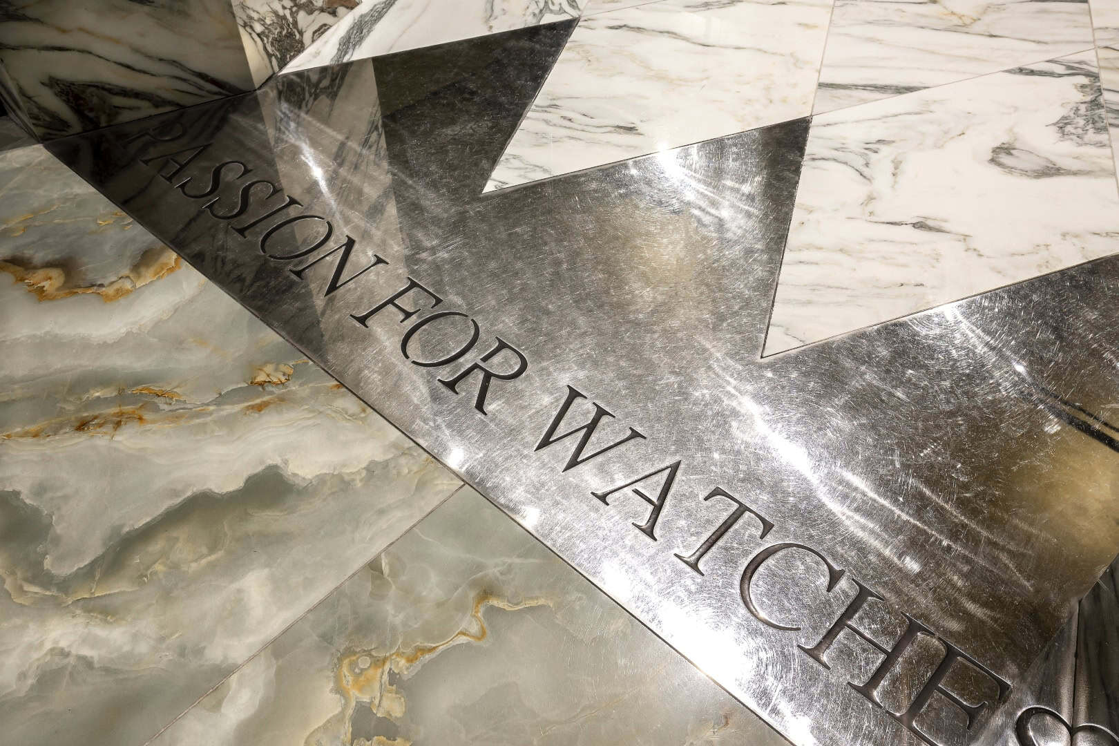 Marble floor with engraved metal plate reading 'Passion for Watches'.
