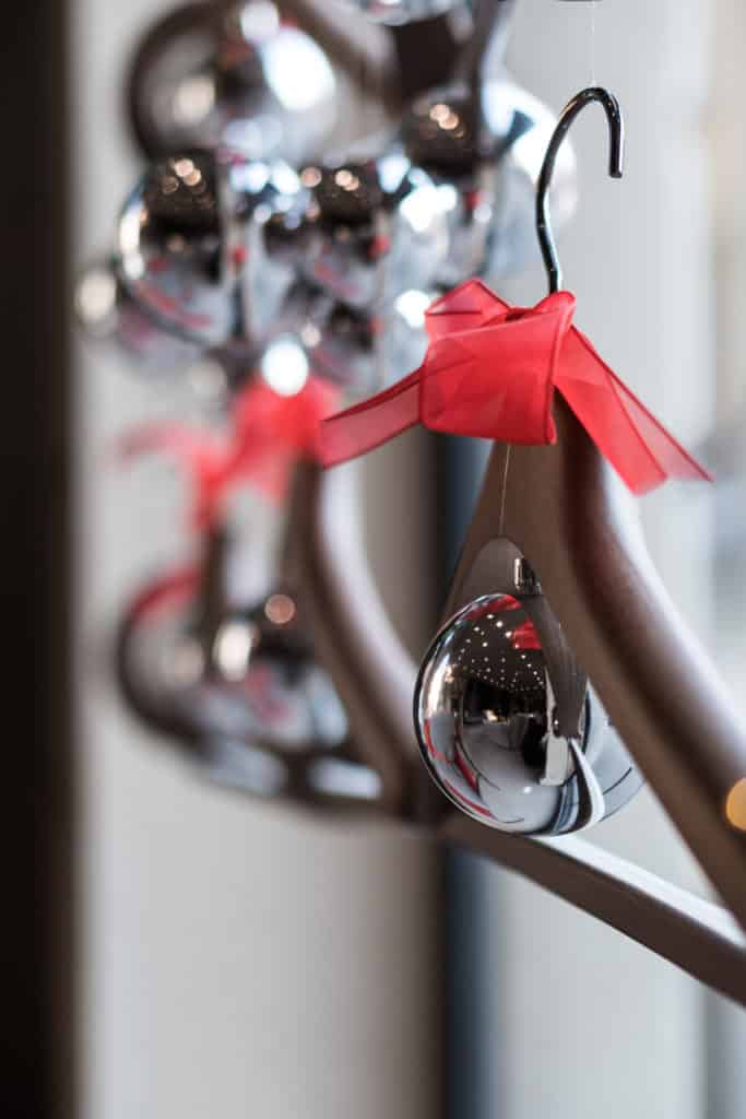 Decorative Christmas Ornaments Hanging On A Metal Rack With Red Ribbons.