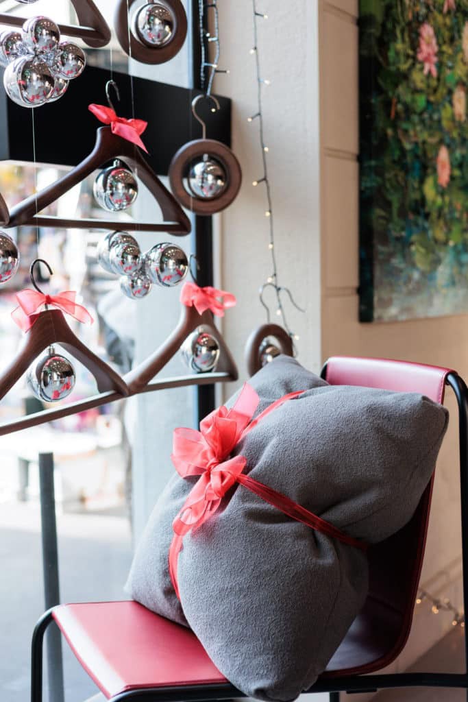 Decorative Christmas Ornaments And A Wrapped Gift On A Pink Chair.